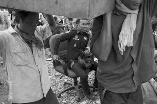 CAMBODIA. Phnom Penh. 4/01/2012: Police watching breakers who dismantle the remaining houses the day after the final eviction of the Borei Keila community.