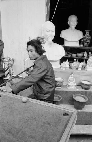 VIETNAM. Hanoi. 25/02/90. Playing pool in front of Ho Chi Minh busts.
