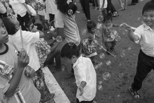 CAMBODIA. Phnom Penh. 21/10/2012: Children playing with bubbles on the 7th day after the death of King Norodom Sihanouk, when Cambodians are showing up massively to pay respect to their king in front of the Royal Palace.