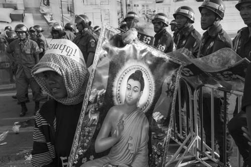 CAMBODIA. Phnom Penh. 26/12/2012: Activist carrying the a picture of Buddha during demonstration of supporters from the Boeung Kak Lake and the Borei Keila communities at the trial of Tim Sakmony and Yorm Bopha at the Phnom Penh Municipal Court.