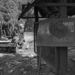 CAMBODIA. Kahchen (Ratanakkiri). 21/02/2013: Tampuon villagers at the rice threshing machine next to a sign of the Cambodian People's Party (ruling party). Most of them are opposed to the construction of the Sesan3 dam and suspect the authorities of not listening to their concerns about depleting fish stocks, floodings, relocation sites and cultural identity.