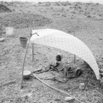 BURKINA FASO. Ouagadougou. 10/03/1985: Child under a shelter while his parents are fishing in the mud along the river banks.