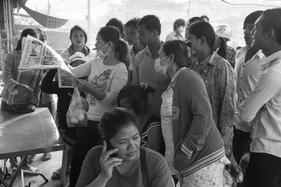 CAMBODIA. Phnom Penh.4/01/2014: Public reading about the events in the newspaper after the violent crackdown on garment workers strike of the day before at Veng Sreng road in the industrial area of Phnom Penh.