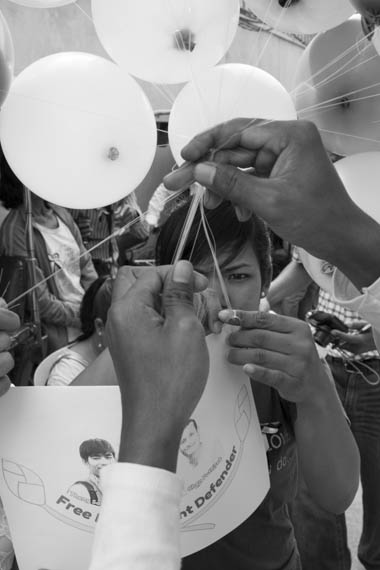 CAMBODIA. Phnom Penh. 10/01/2014: Activists attaching an image representing three arrested union leaders and activists to ballooons after a ceremony for the crackdown victims and a press conference at Solidarity House requesting the release of the 23 arrested during the latest crackdown on striking factory workers , a halt to violence and a salary rise to 160$.