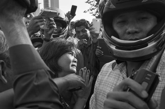 CAMBODIA. Phnom Penh. 14/01/2014: Mu Sochua, CNRP MP, pleading and singing to helmeted thugs hired by the Municipality while Sam Rainsy and Kem Sokha, opposition CNRP co-Presidents, and Rong Chhun, Leader of the Independent Teachers Association, are summonsed at the Phnom Penh Municipal Court, to answer questions about their alleged incitement to violence during the weeks-long workers srike.