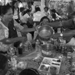 CAMBODIA. Phnom Penh. 15/01/2014: Guests enjoy a meal before a buddhist ceremony organised by the Boeung Kak lake community to commemorate the 4 garment workers who were killed on January 3rd, during a violent crackdown by the army on a workers' strike.