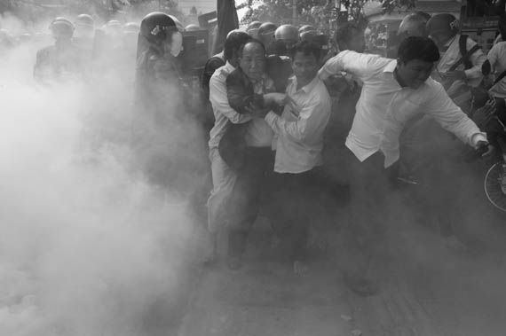 CAMBODIA. Phnom Penh. 27/01/2014: Mam Sonando, Director of Beehive Radio, being whisked away through smoke bombs by supporters during a protest march to the Ministry of Information to request a TV frequency which was dispersed by riot police.