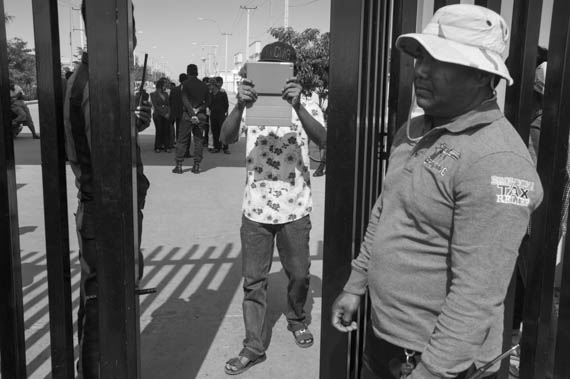 CAMBODIA. Dangkor (Phnom Penh). 28/01/2014: Guards at the entrance of the industrial area of Vattanac II photographing journalists when about 1000 garment factory workers walked out after 11 union leaders were fired.