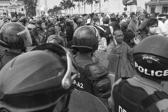 CAMBODIA. Phnom Penh. 11/02/2014: After the Appeals Court issued a no bail verdict to the 21 who were arrested during the violent military crackdown on working strikers on January2nd and 3d, a small group, led by But Bunthen from the Independent Monk Network for Social Justice (IMNSJ), here seen being chased away by riot police forces, gathered at the Preah Ang Dong riverside pagoda before being dispersed by an important riot police force when marching towards the Royal Palace.