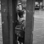 CAMBODIA, Phnom Penh. 4/07/2014: Schoolchildren wait for their moto dup after a heavy rain flooded Sothearos Boulevard.