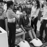 CAMBODIA, Phnom Penh. 6/07/2014: Four sales people convincing a hestitant customer to buy a foot massage machine at the first Aeon shopping mall in Phnom Penh which opened 2 weeks ago and turns out to be a huge popular success.